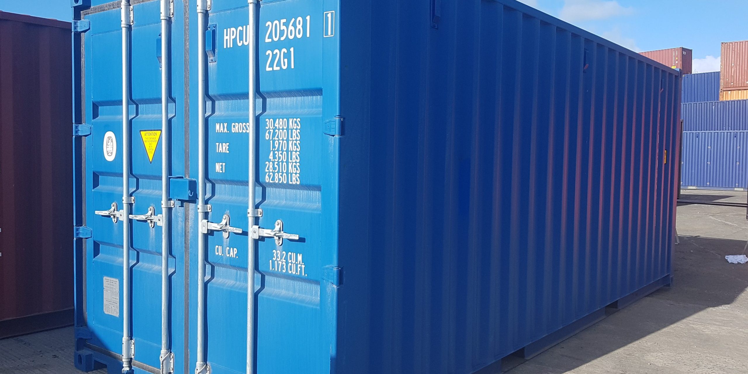 A blue shipping container outside on a clear, sunny day.