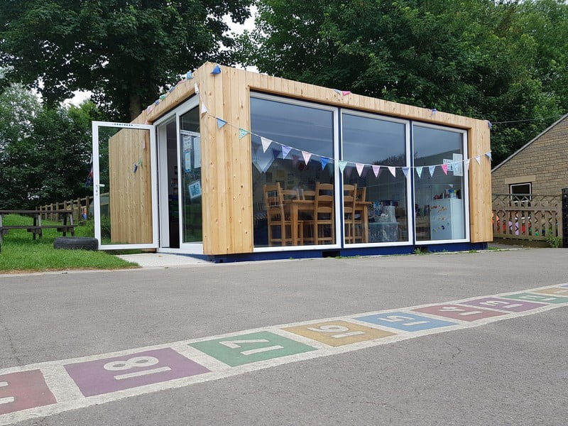 An outdoor shipping container classroom with full-length windows.