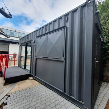 External view of container coffee shop with accessibility ramp and floor-length window.