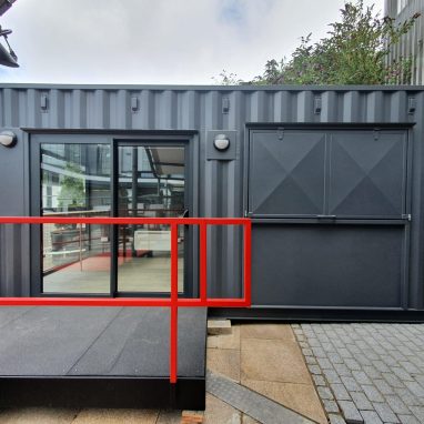 External view of container coffee shop with accessibility ramp and floor-length window.