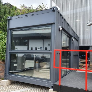 External view of container coffee shop with accessibility ramp and floor-length window.