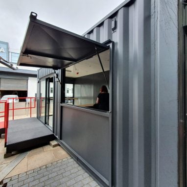 External view of container coffee shop with accessibility ramp and floor-length window.